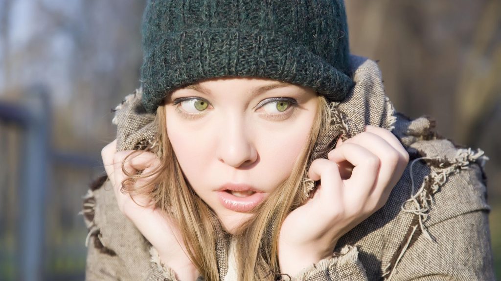 A close up of a young girl cowering in her coat collar