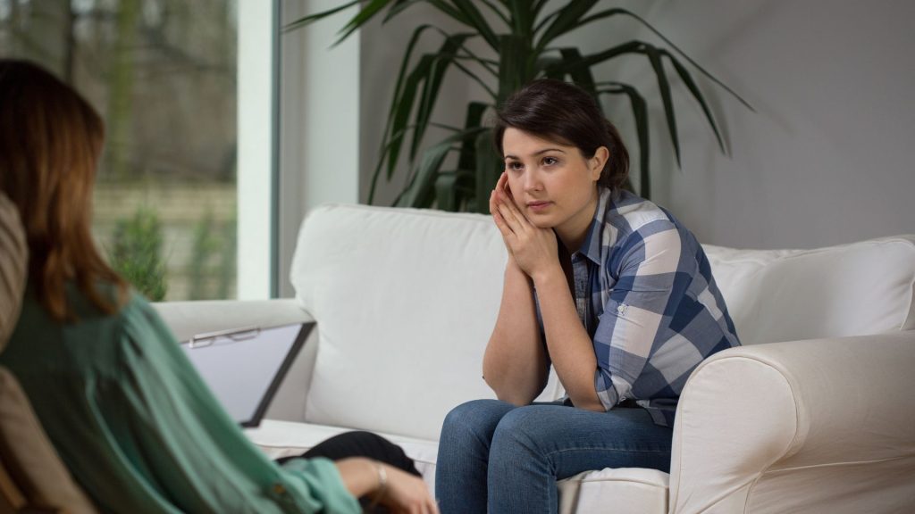 A woman in a plaid shirt pays attention to her therapist