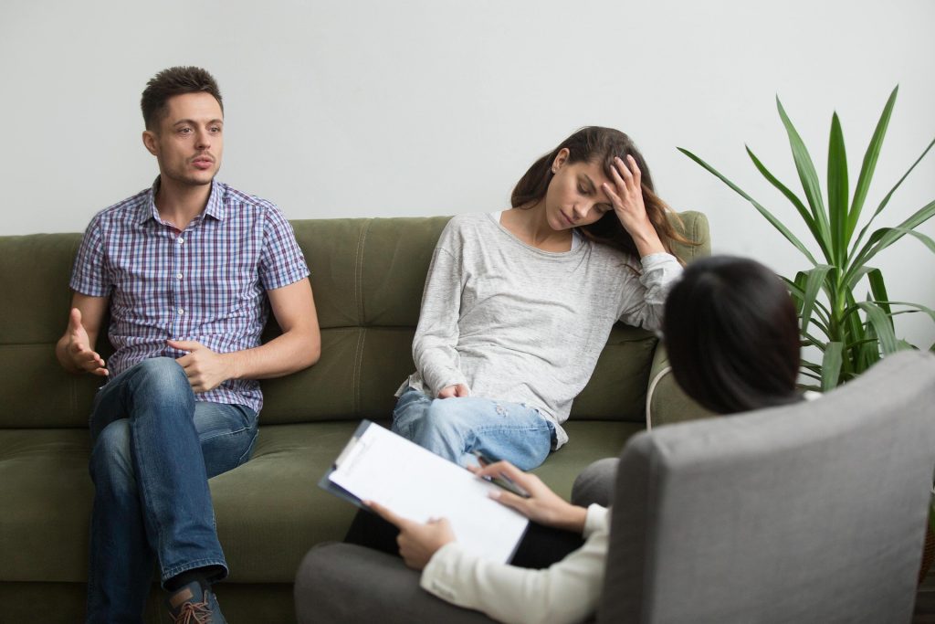 A couple on a green couch speak with a counselor