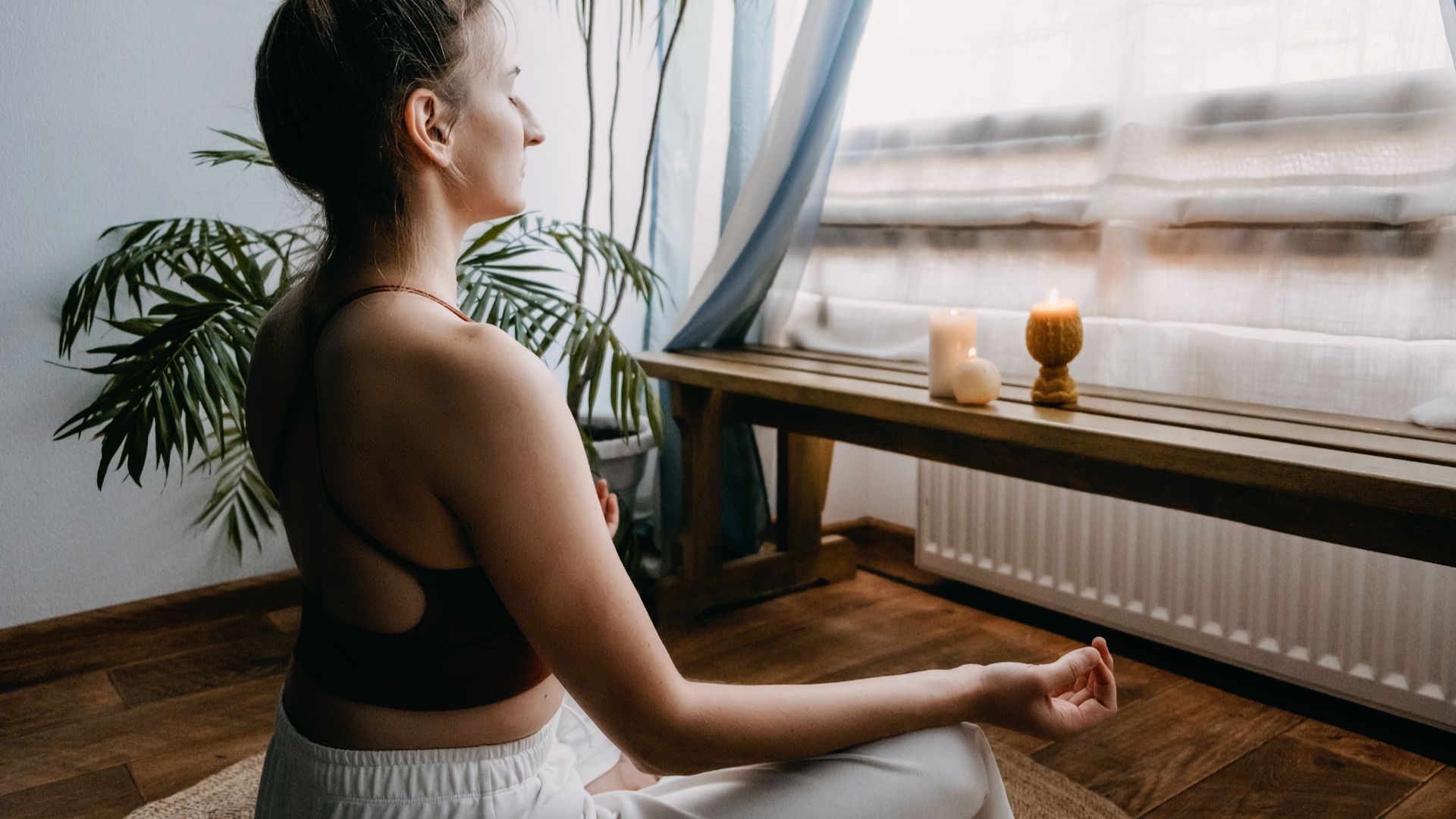 A woman performing yoga in a studio with candles and plants