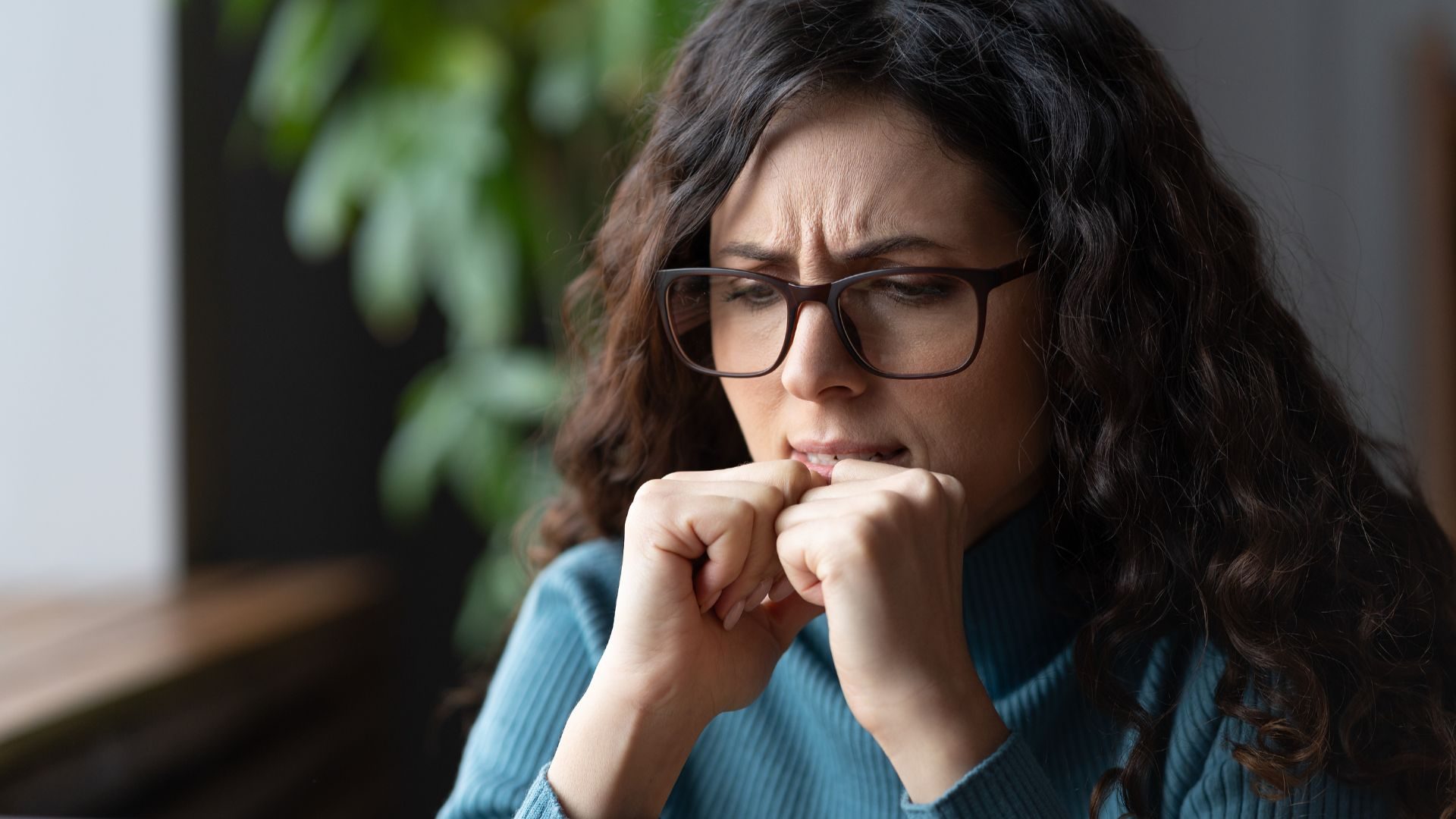 An anxious looking woman squeezes her fists
