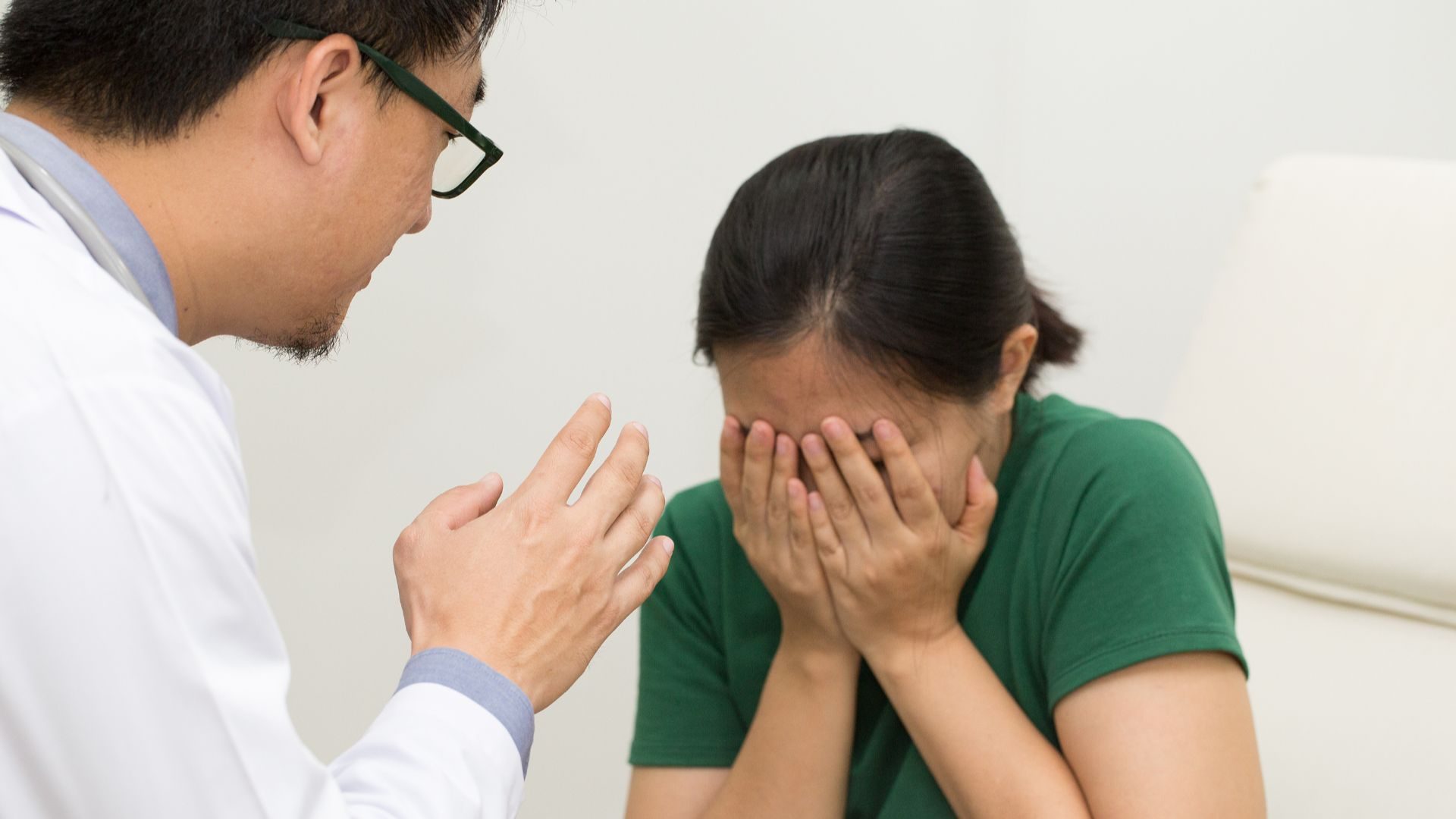A girl covers her face crying while a doctor tries to help