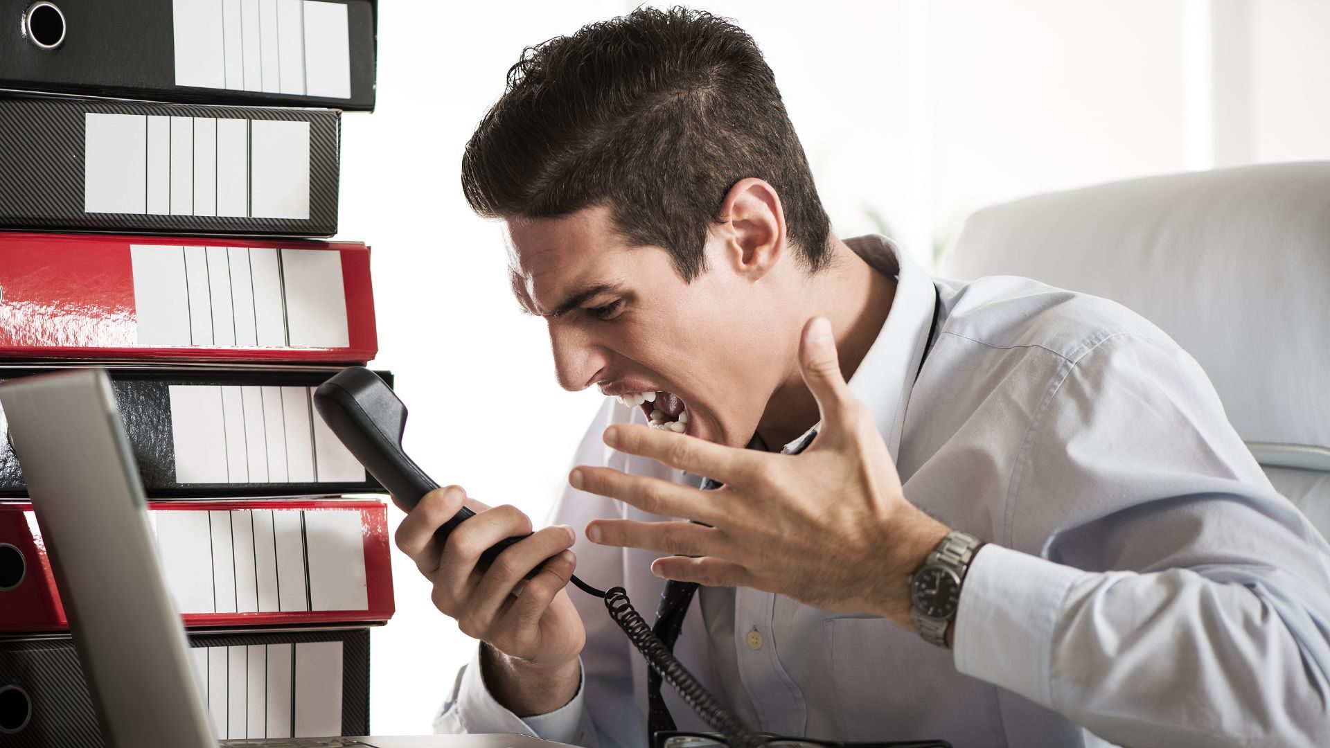 A man screams into a telephone out of obvious anger