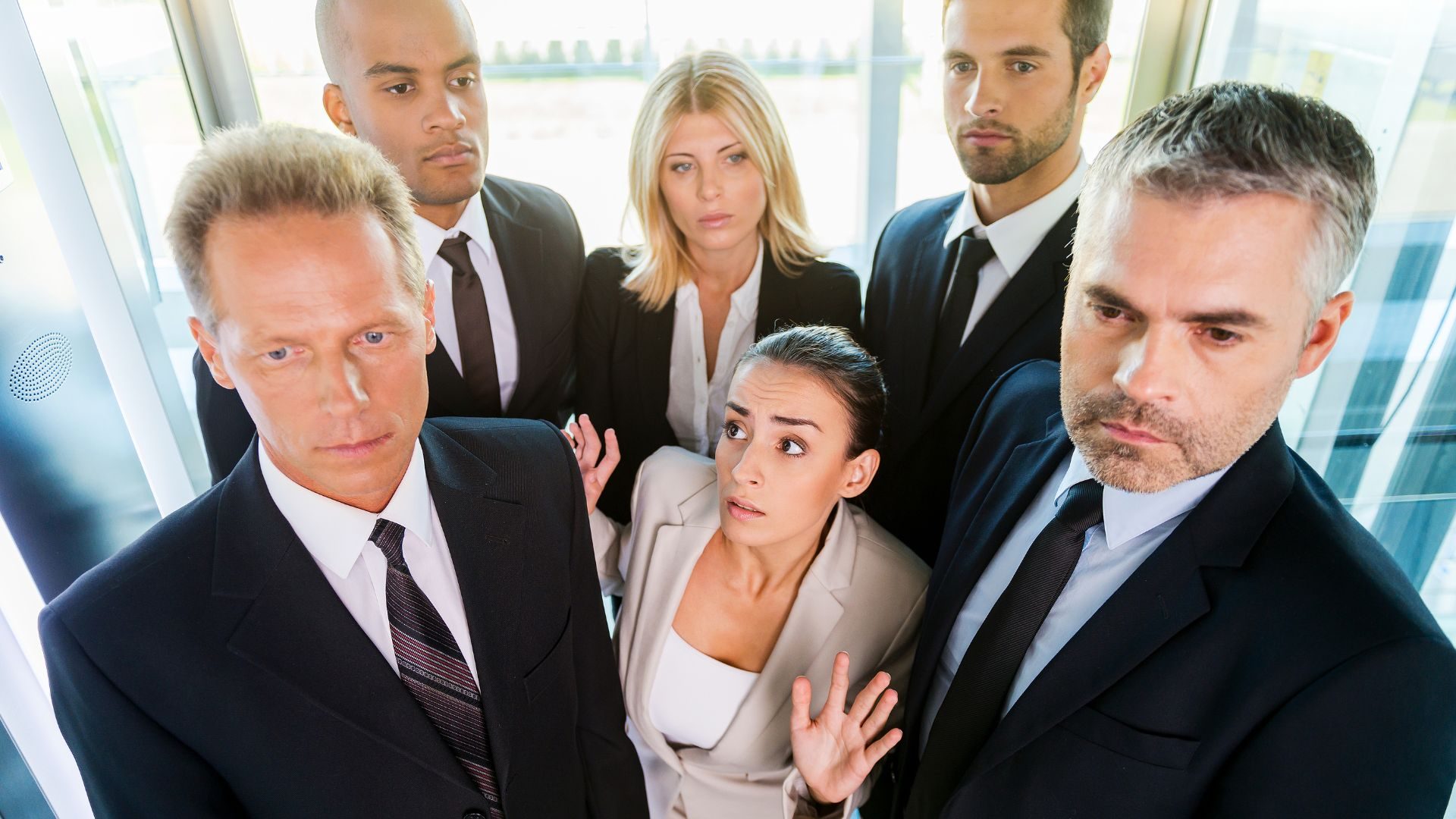 A woman surrounded closely by people in an elevator