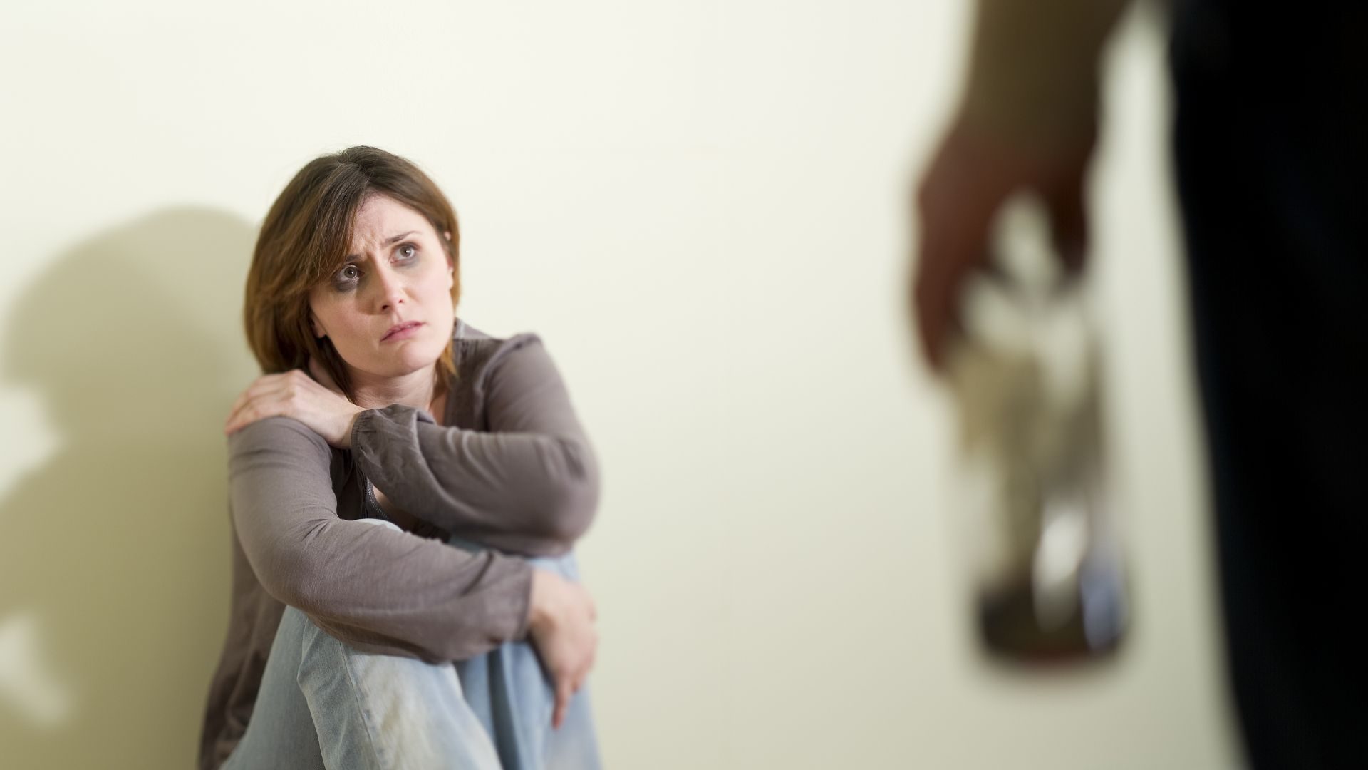 A domestic violence victim with a black eye sitting on a floor