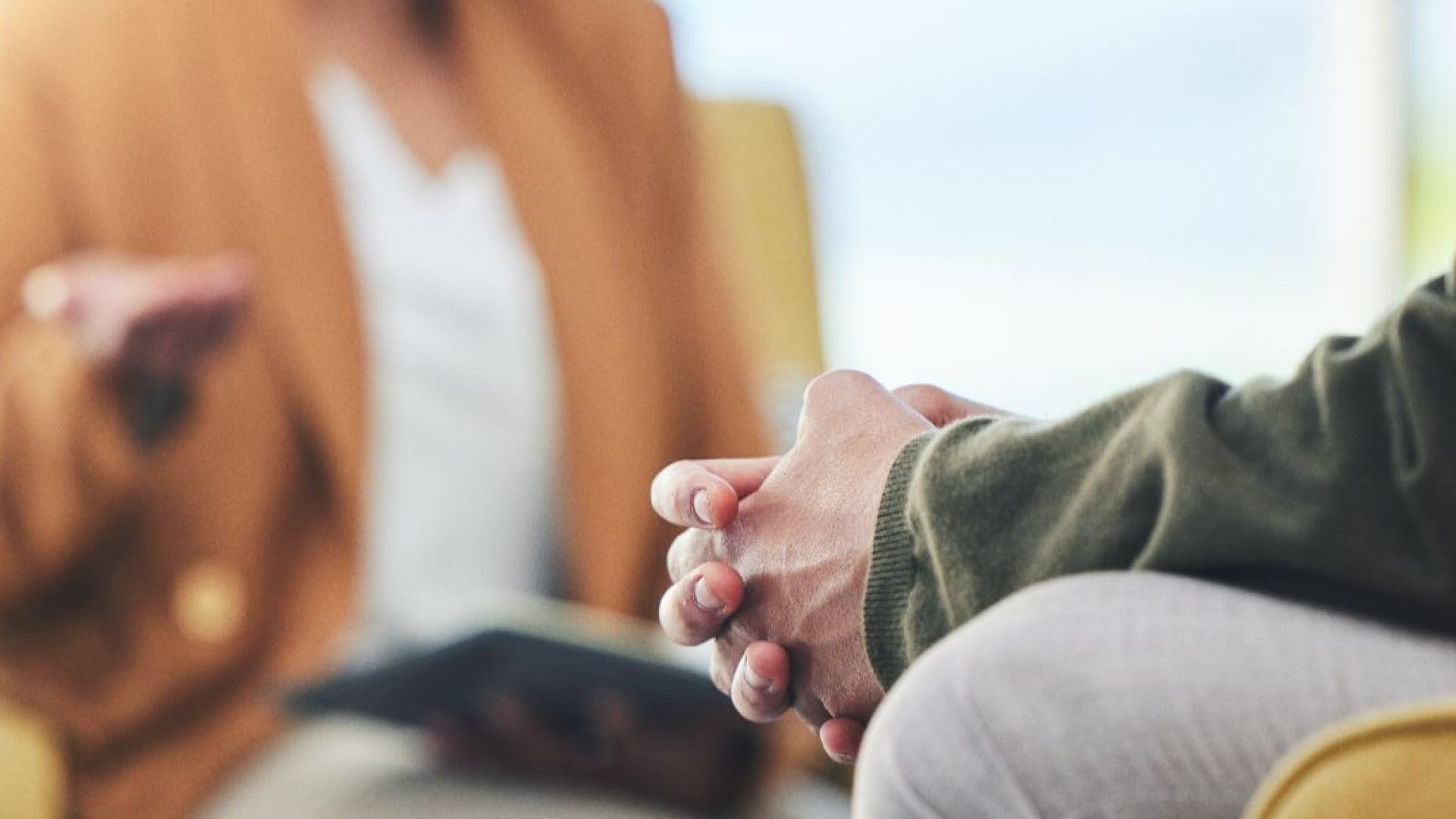 A therapist talks to a patient, only hands and bodies visible.