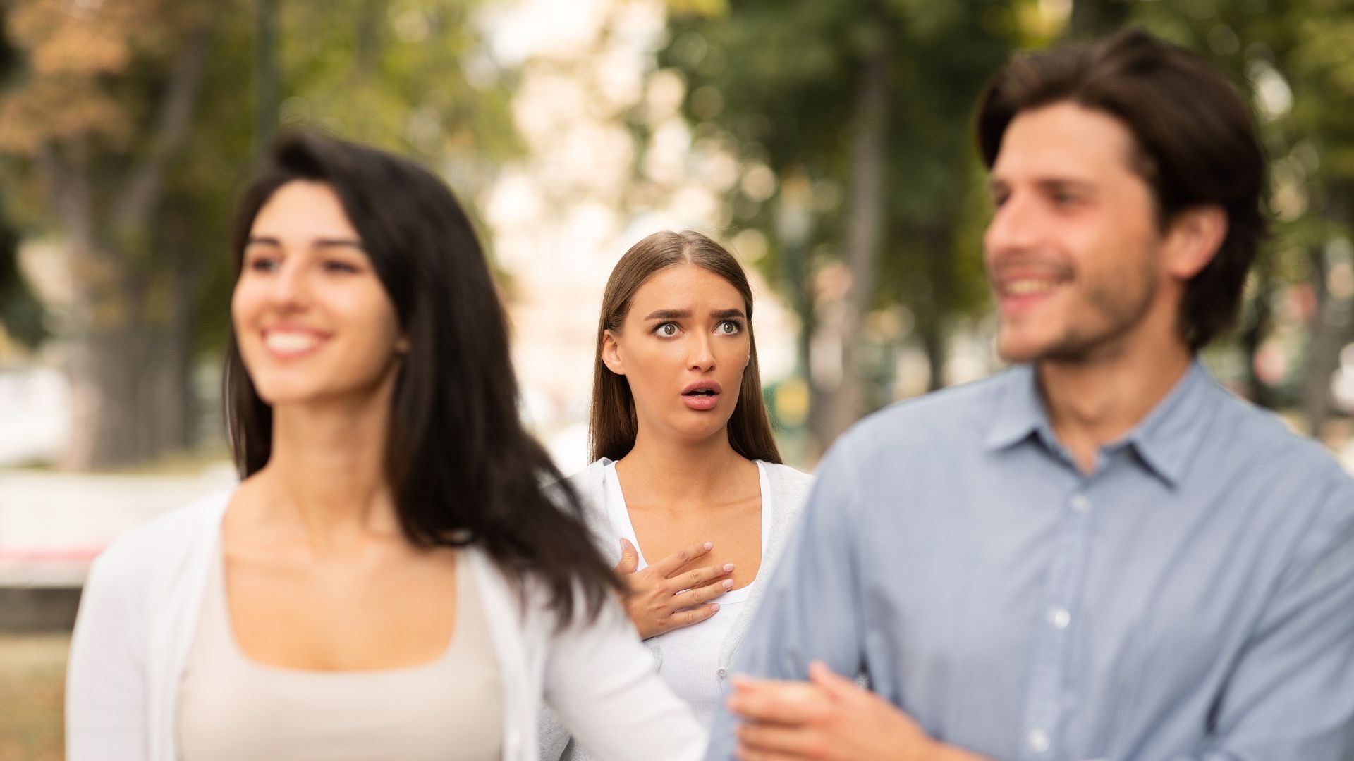 A woman looks surprised and/or hurt to see another man and woman