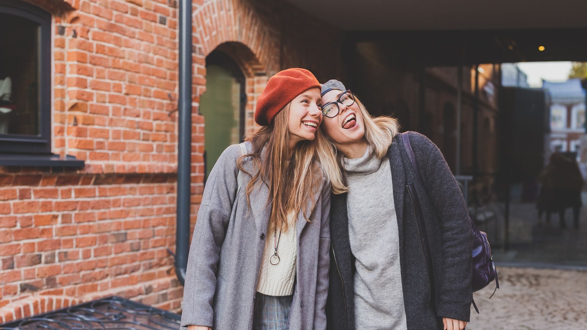 Two 20-something women make happy faces on a city street