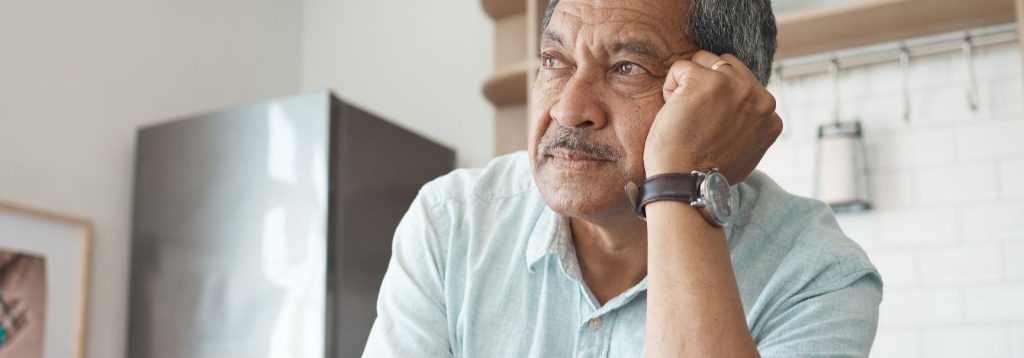 Someone sits in a kitchen, looking worried.