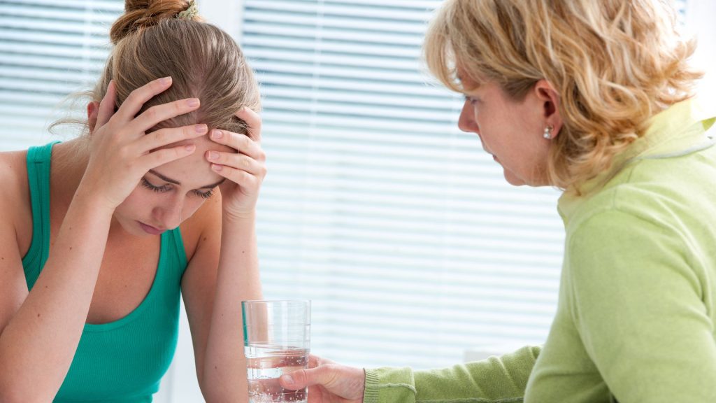 An older woman comforts her daughter in the kitchen